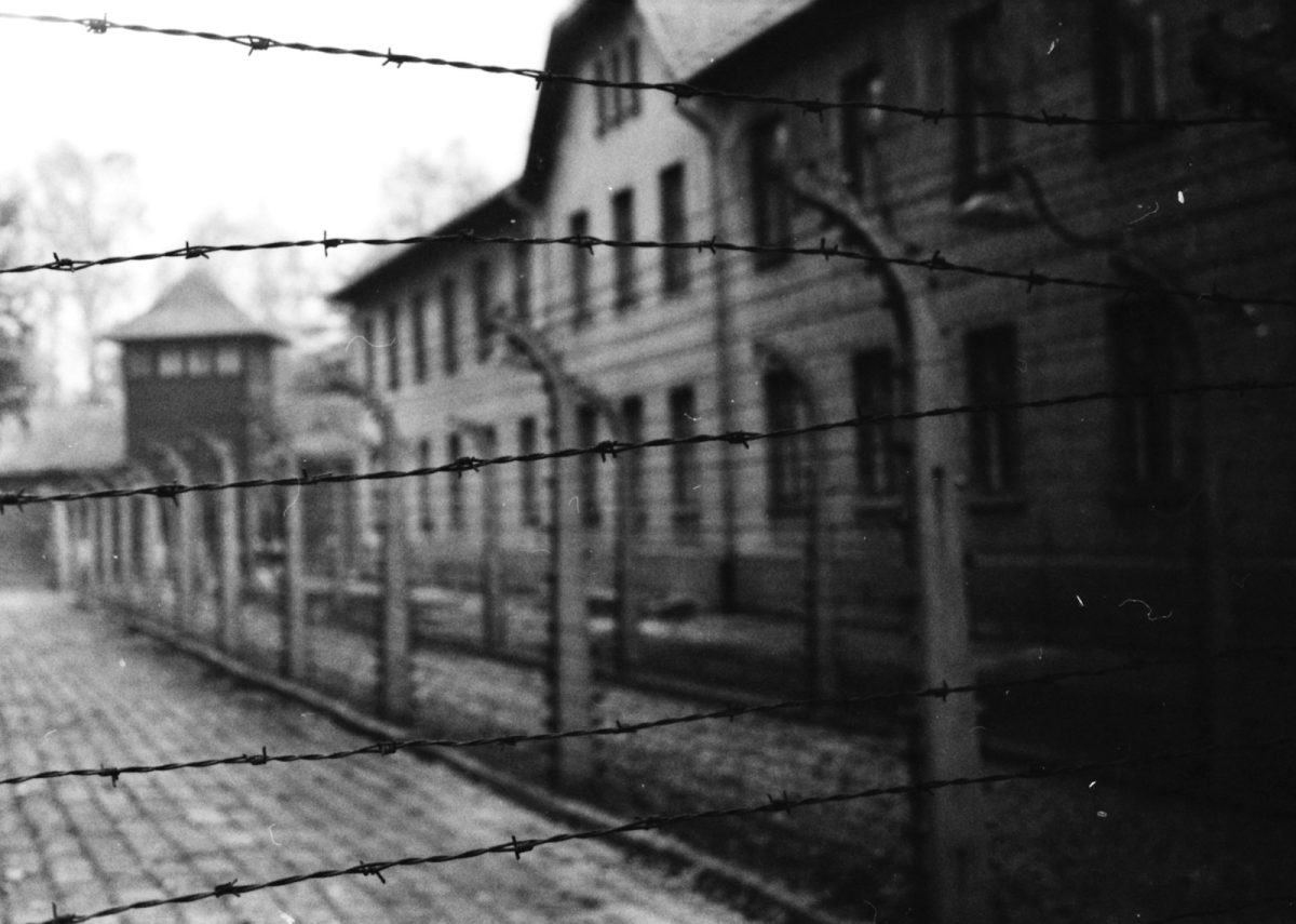 a black and white photo of a building behind a barbed wire fence