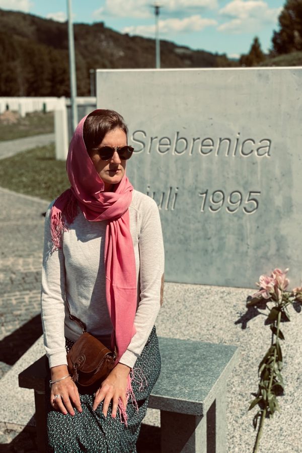 a woman sitting on a bench in front of a memorial