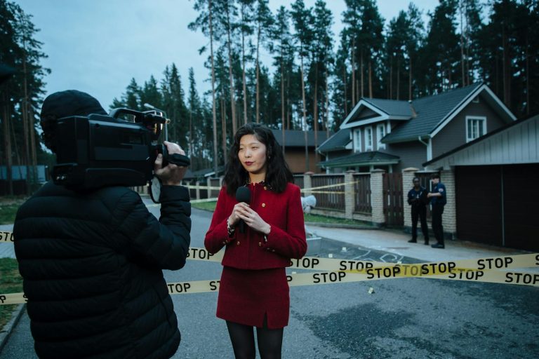 Journalist reporting live from a taped crime scene with cameraman and police