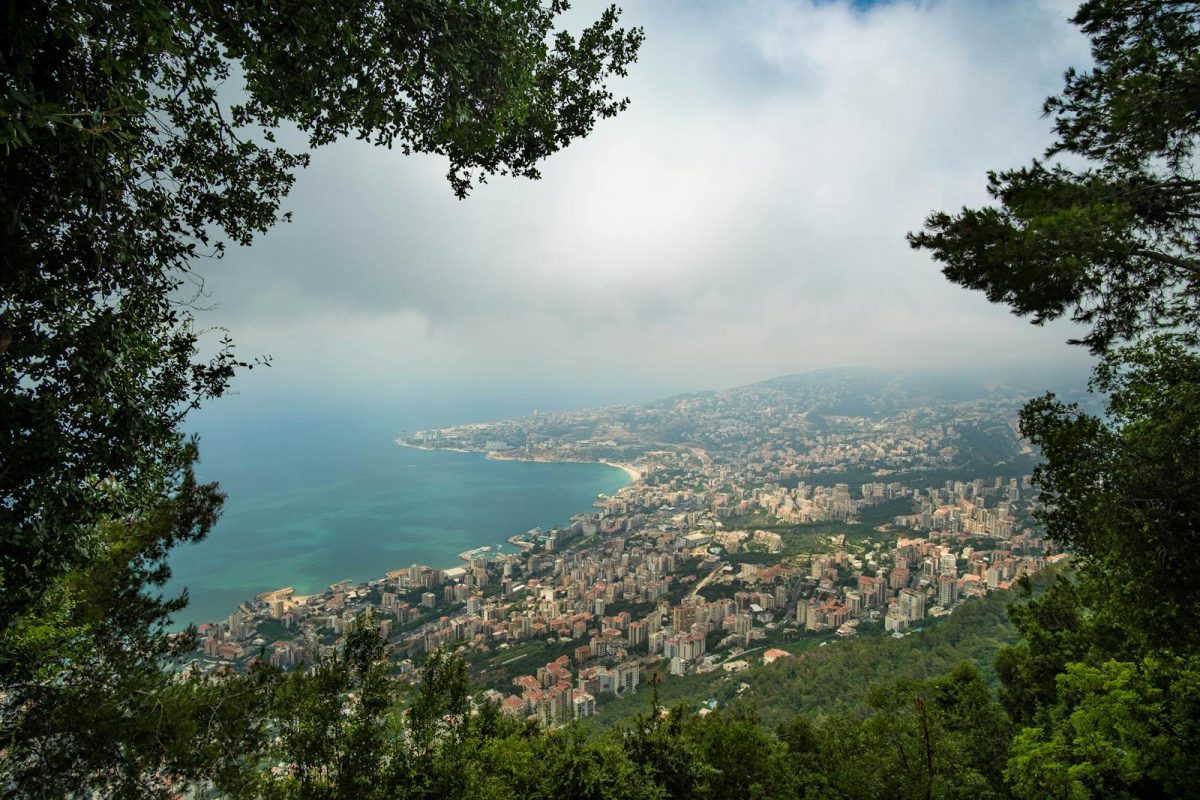 Breathtaking aerial view of Harissa, Lebanon's coastline, framed by lush greenery on a hazy day.
