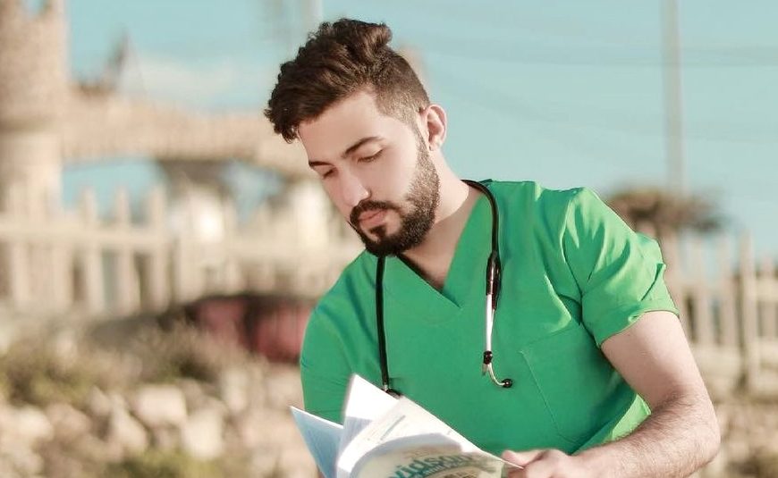 Dr. Dr. Ahmed Nawaf Hajjaj in green scrubs, reading before saving lives in Gaza