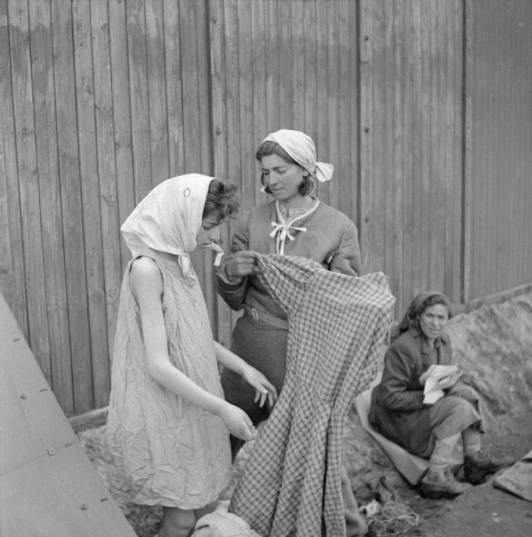 Woman helping girl dress herself during liberation of Bergen-Belsen Concentration Camp
