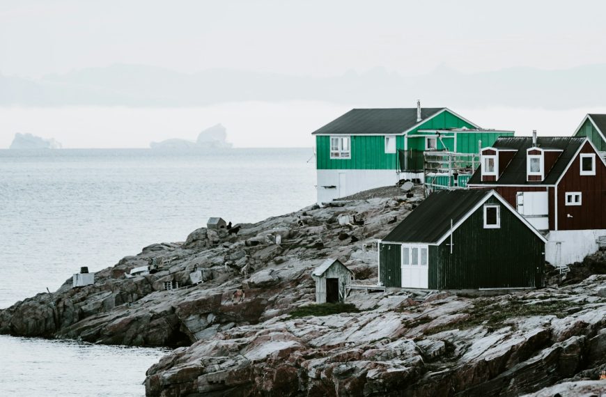 green and black house near body of water under white sky