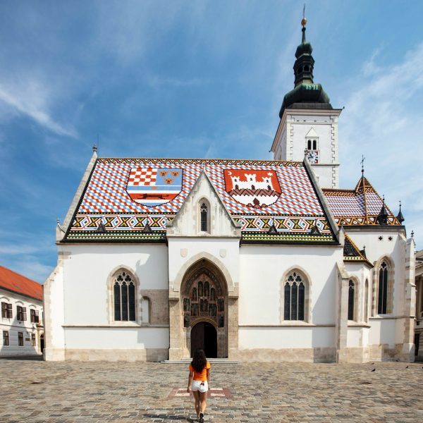 a person standing in front of a white building with a red roof