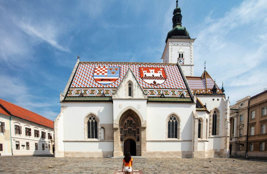 a person standing in front of a white building with a red roof